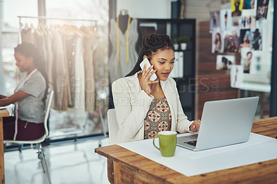 Buy stock photo Shot of a fashion designer talking on her cellphone while using her laptop