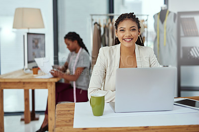 Buy stock photo Cropped portrait of a young fashion designer working on her laptop with a colleague in the background