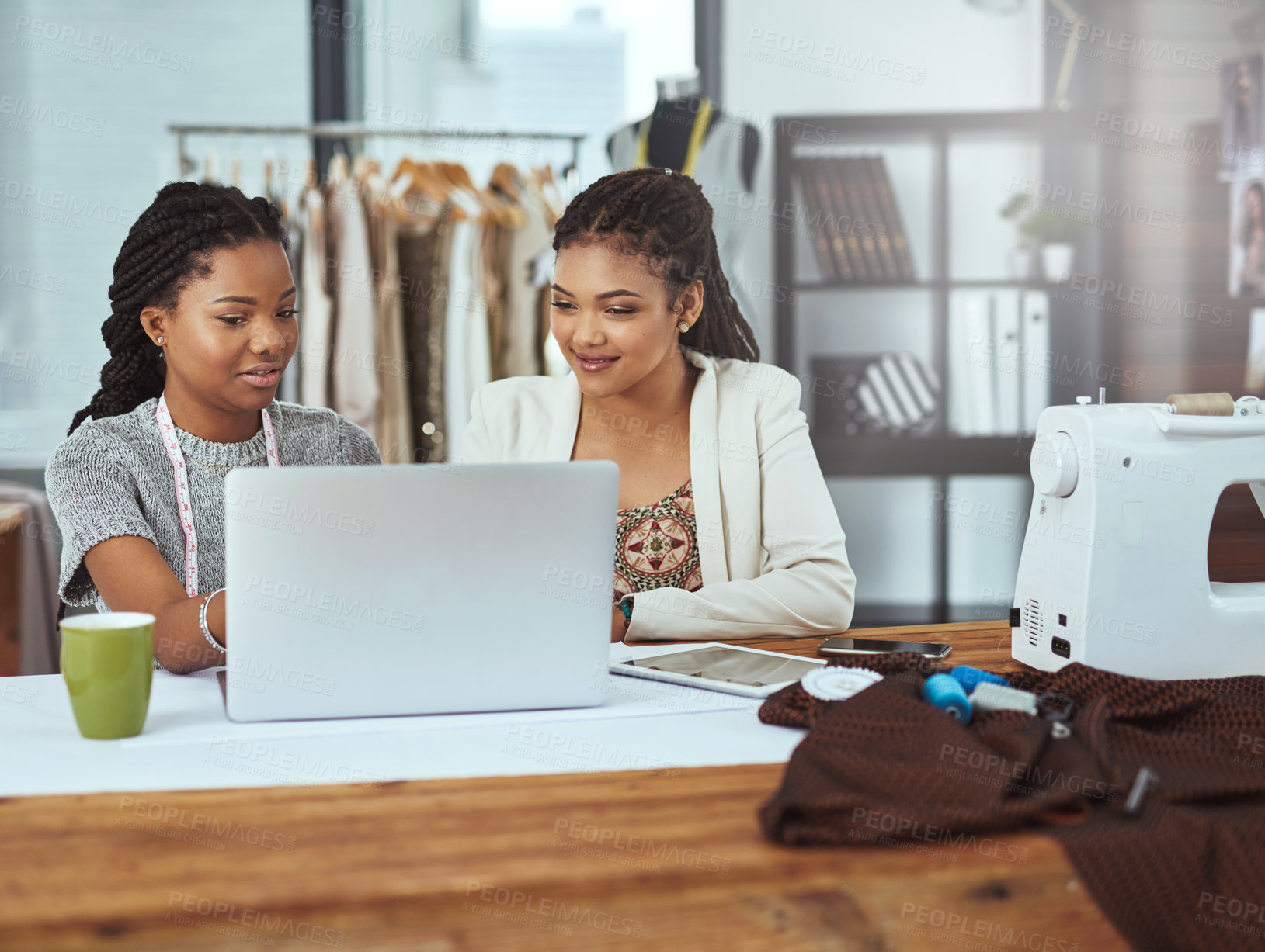 Buy stock photo Cropped shot of two young fashion designers working on a laptop