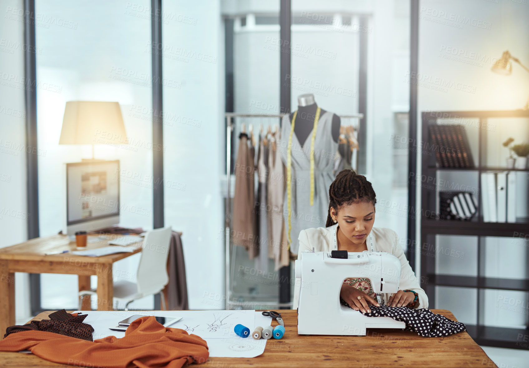 Buy stock photo Cropped shot of a young fashion designer using a sewing machine in her workshop