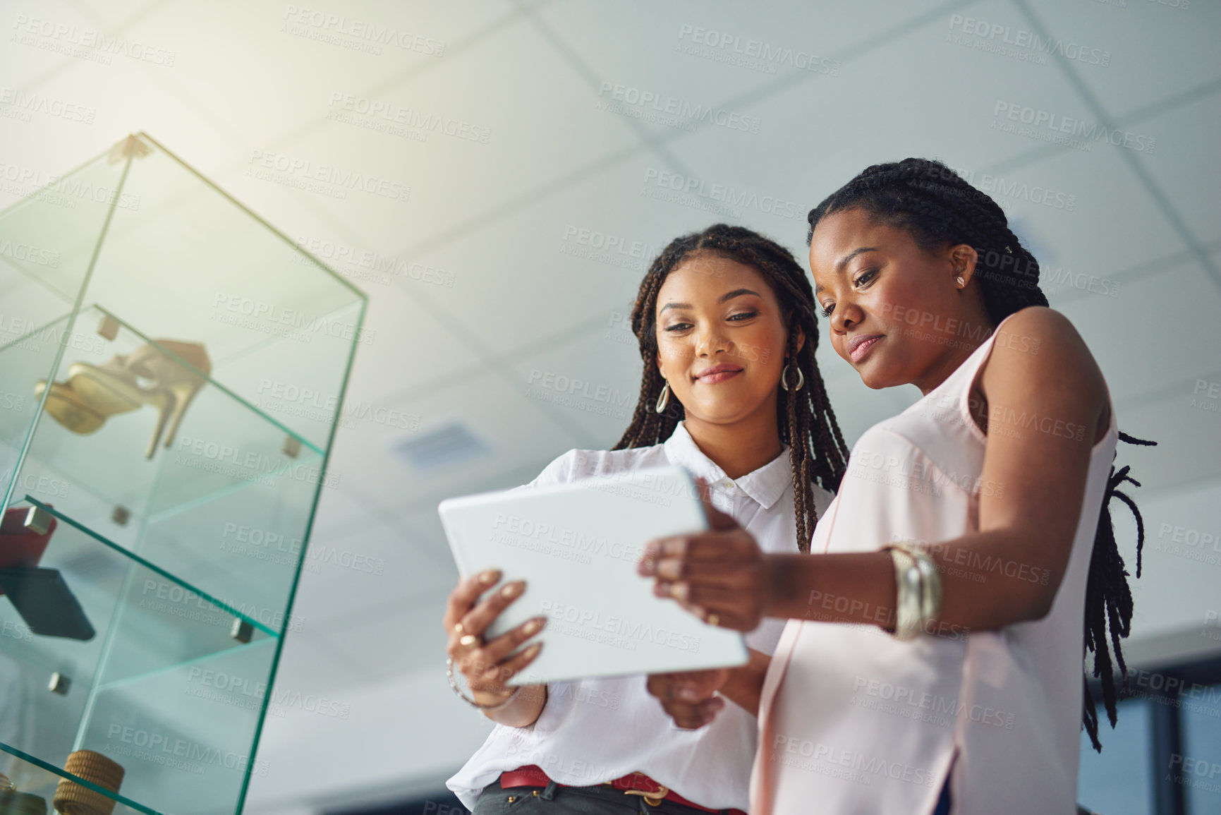 Buy stock photo Cropped shot of young business partners working on a digital tablet together