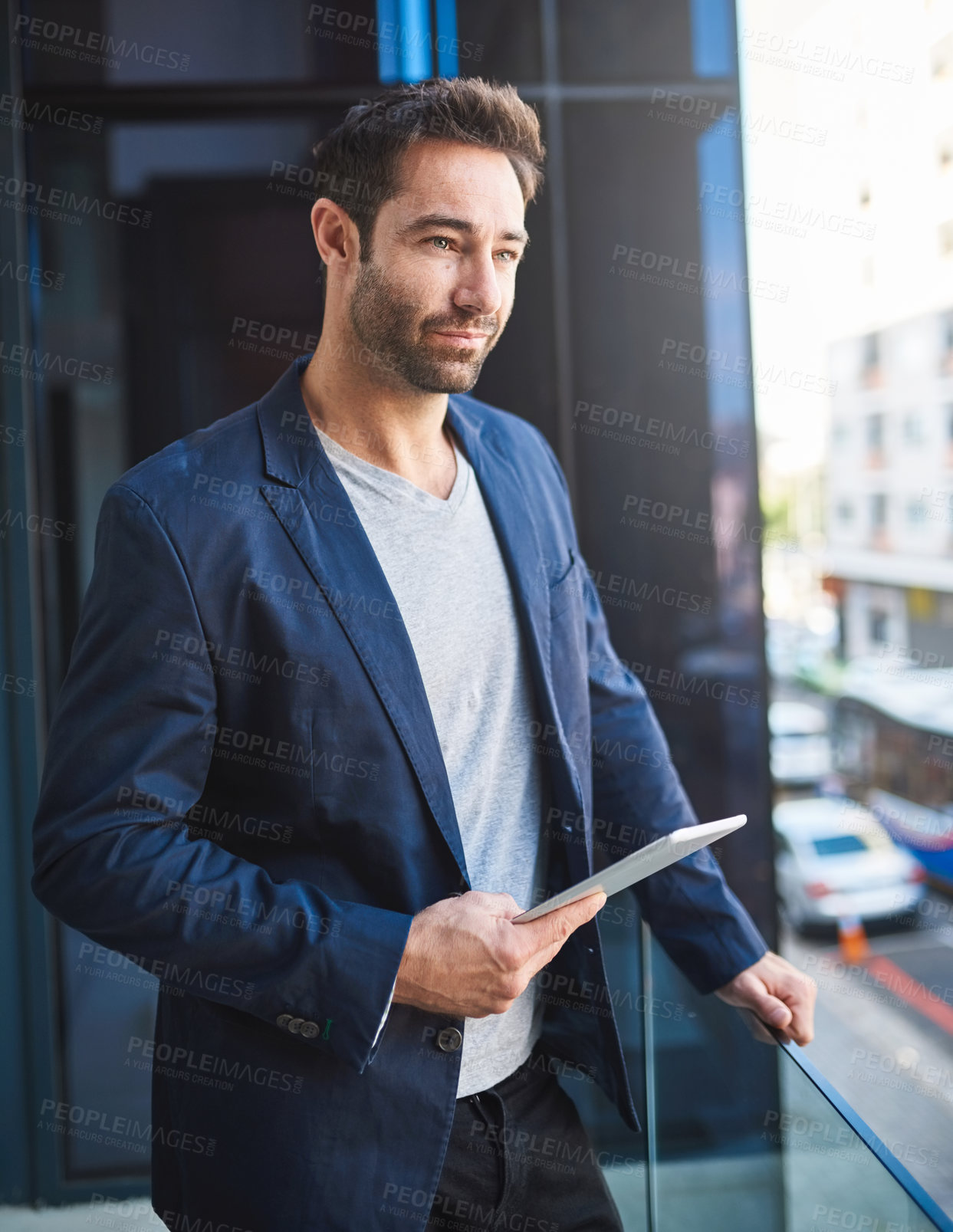 Buy stock photo Cropped shot of a businessman using his tablet while standing on a balcony