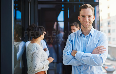 Buy stock photo Portrait of a businessman standing on a balcony with his arms crossed and his coworkers in the background