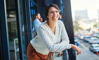 Buy stock photo Cropped shot of a young businesswoman standing on a balcony with her coworkers in the background