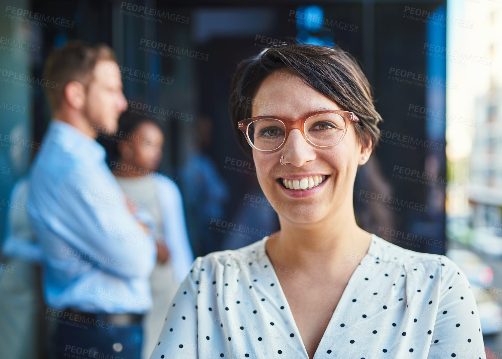 Buy stock photo Cropped shot of a young businesswoman standing on a balcony with her coworkers in the background