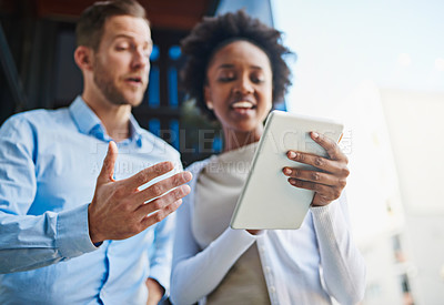 Buy stock photo Cropped shot of two coworkers using a digital tablet while standing on a balcony