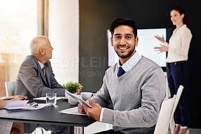 Buy stock photo Portrait of a young businessman sitting in a boardroom with colleagues in the background
