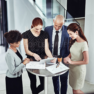 Buy stock photo Shot of a corporate business team using a digital tablet together in a meeting at work