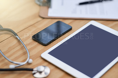 Buy stock photo Closeup shot of a tablet, smartphone, clipboard and stethoscope on a doctor's desk