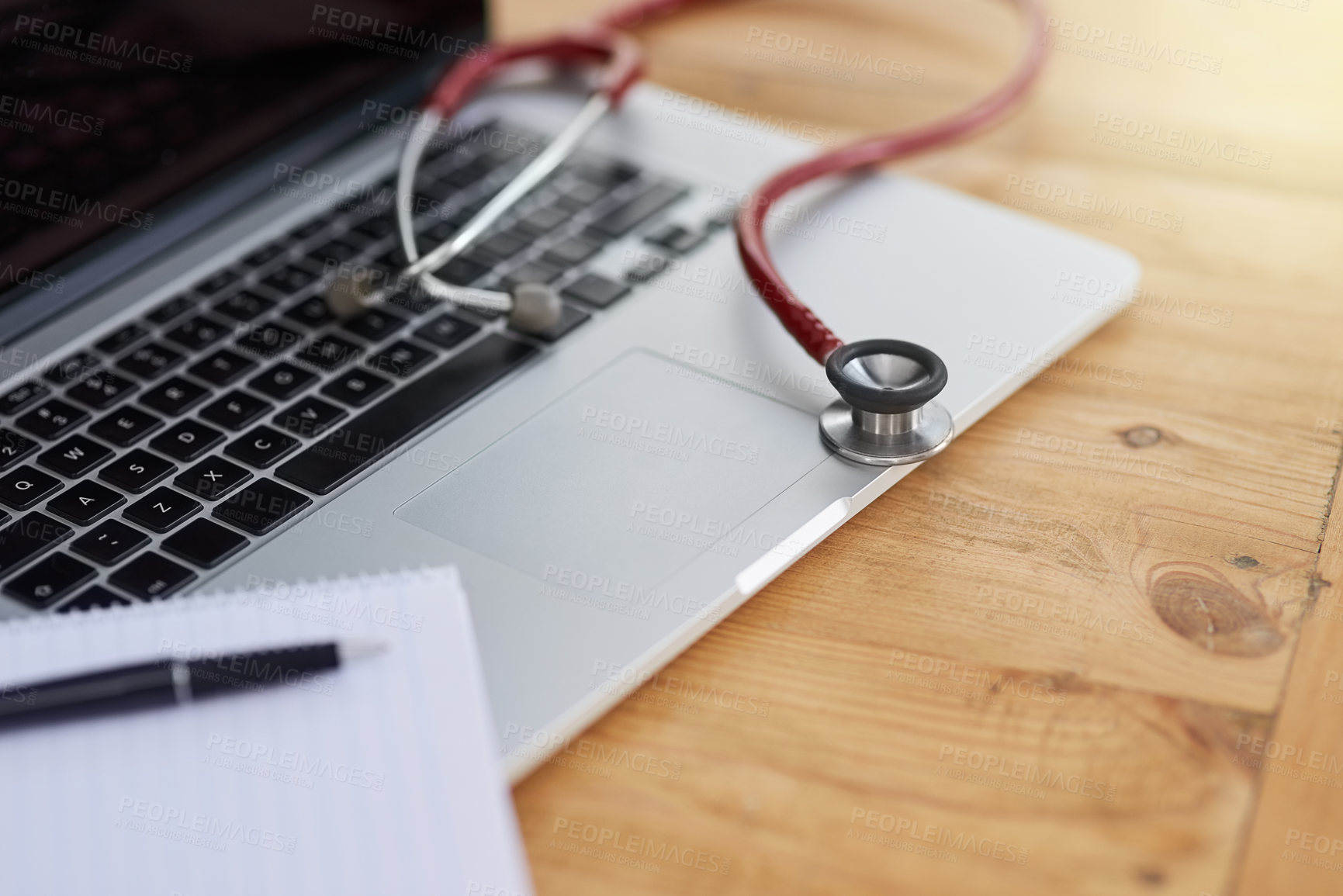 Buy stock photo Closeup shot of a laptop, stethoscope and doctor's notebook on a table
