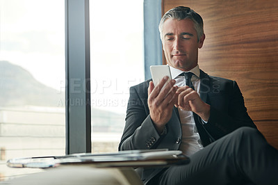 Buy stock photo Shot of a mature businessman using his phone at work