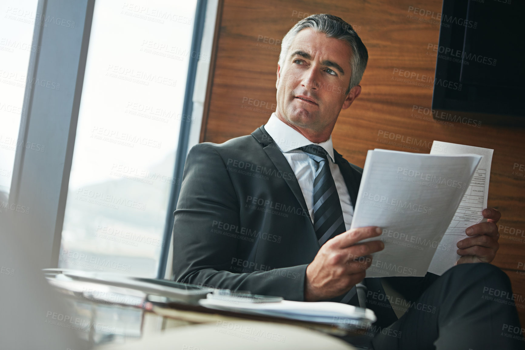 Buy stock photo Shot of a mature businessman going through paperwork at work