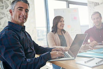 Buy stock photo Portrait of a businessman working on his laptop while in a meeting with colleagues