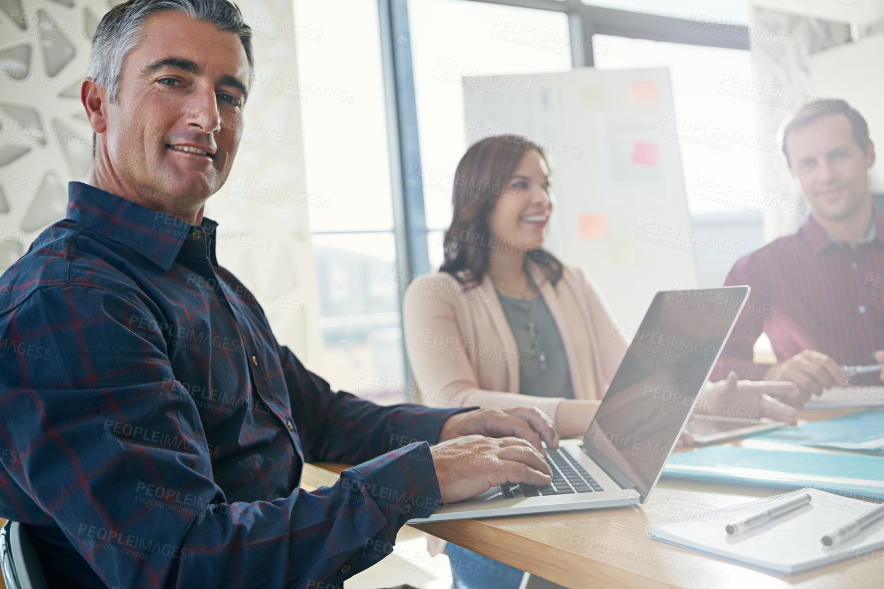 Buy stock photo Portrait of a businessman working on his laptop while in a meeting with colleagues