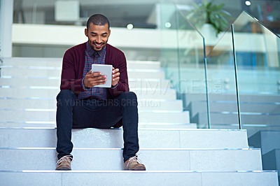 Buy stock photo Shot of a young businessman using a digital tablet on the stairs in a modern office