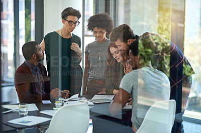 Buy stock photo Cropped shot of a group of creatives working together on a digital tablet in a modern office