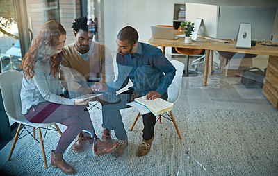 Buy stock photo Shot of a group of creatives working together on a digital tablet in a modern office