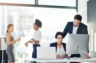 Buy stock photo Cropped shot of two businesspeople working in her office with colleagues in the background