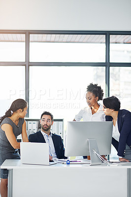 Buy stock photo Cropped shot of a group of businesspeople gathered around a computer in their office