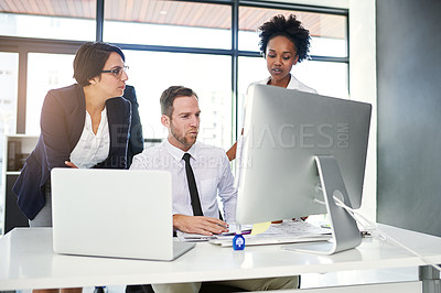 Buy stock photo Cropped shot of a group of businesspeople gathered around a computer in their office