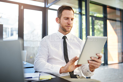 Buy stock photo Cropped shot of a businessman working on a digital tablet in a modern office