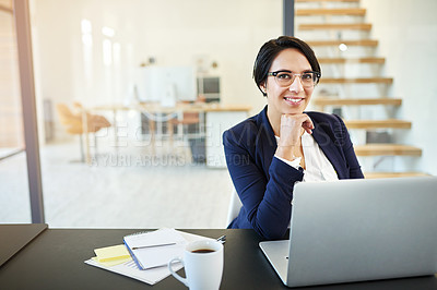 Buy stock photo Portrait of a confident young businesswoman working on a laptop in a modern office