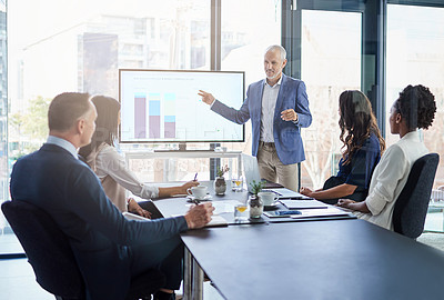 Buy stock photo Sales manager gives a presentation on marketing and brand strategy in a boardroom meeting. Successful, corporate and mature male leader points to a graph on the monitor screen to show the planning