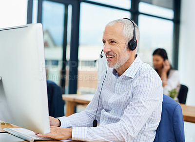 Buy stock photo Cropped shot of a mature businessman working in his office with colleagues in the background