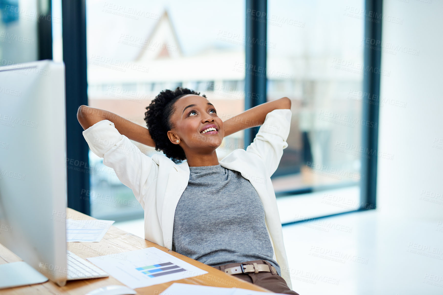 Buy stock photo Cropped shot of a young woman sitting with her hands behind her head in the office