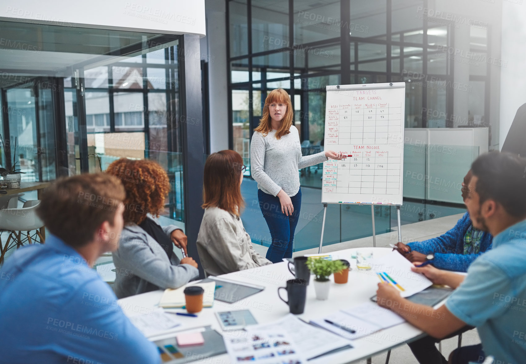 Buy stock photo Shot of a young businesswoman using a whiteboard to give a presentation to her colleagues in a boardroom