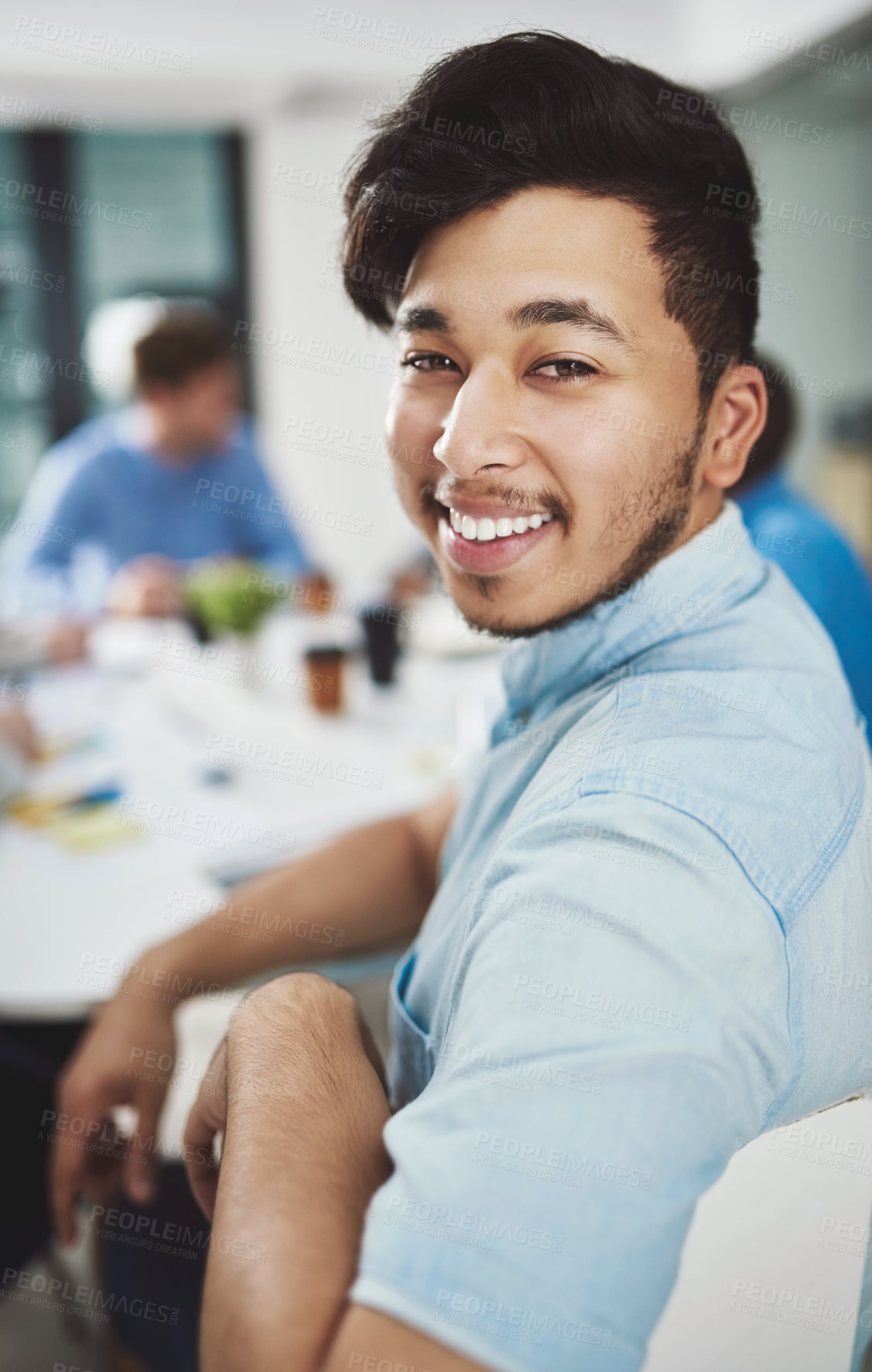 Buy stock photo Cropped portrait of a young businessman looking over his shoulder during a presentation in a boardroom