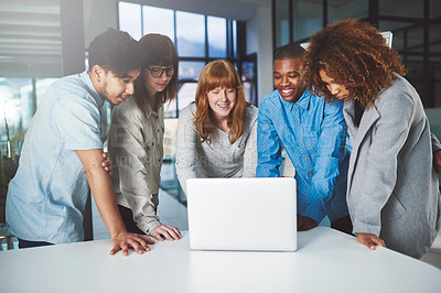 Buy stock photo Cropped shot of a group of young businesspeople huddled around a laptop in their office