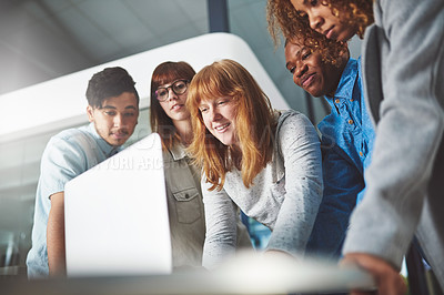 Buy stock photo Cropped shot of a group of young businesspeople huddled around a laptop in their office