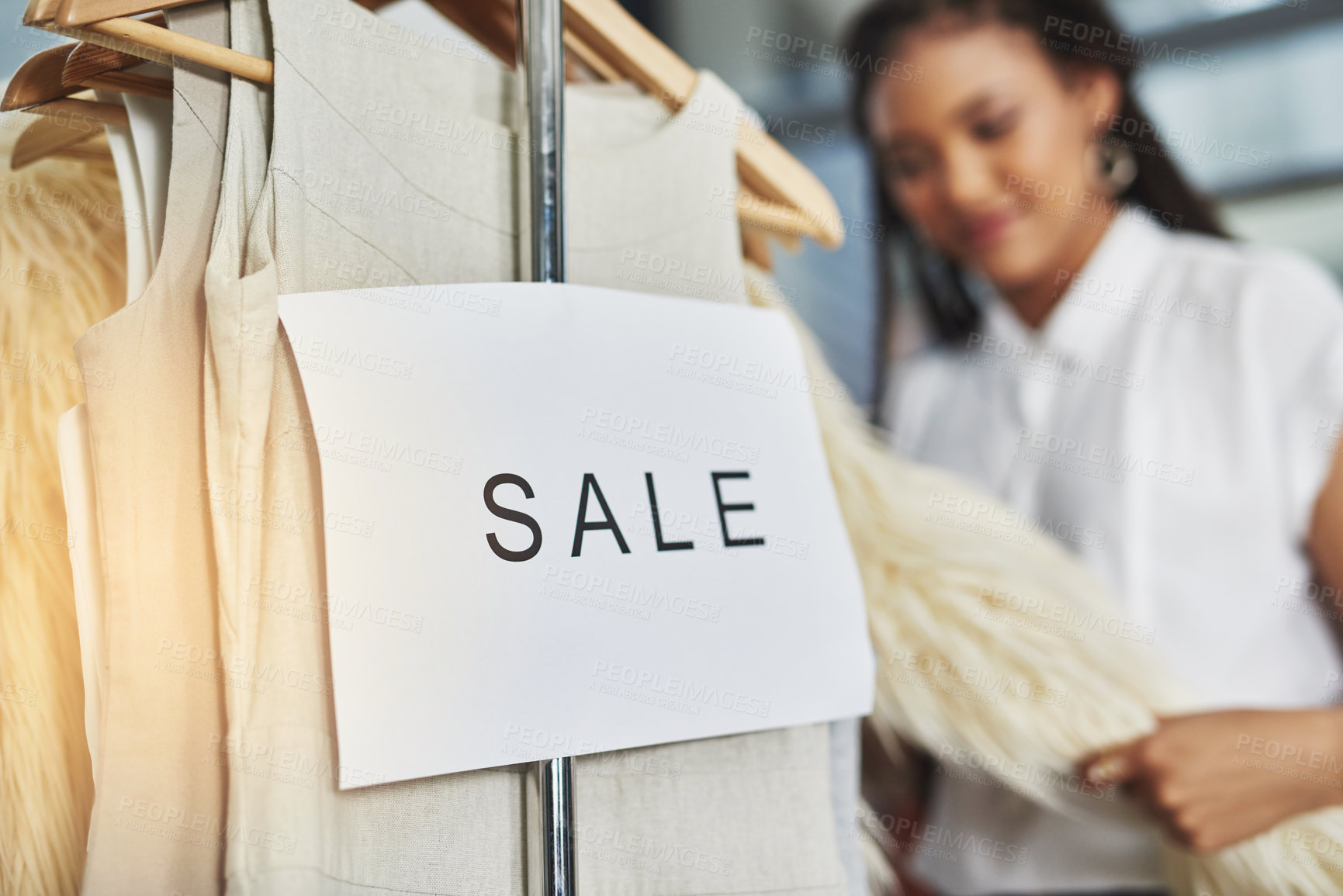 Buy stock photo Cropped shot of a woman looking at dresses on a rail with a sign that reads 