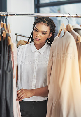 Buy stock photo Cropped shot of a woman looking at clothes on a rail in a store