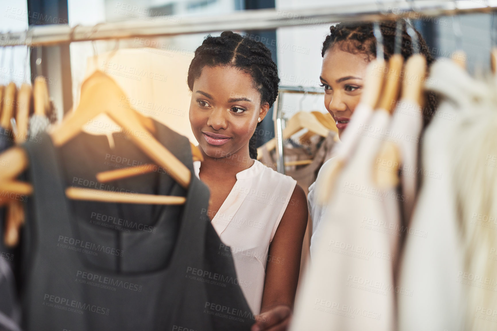 Buy stock photo Cropped shot of two women looking at clothes on a rail in a store