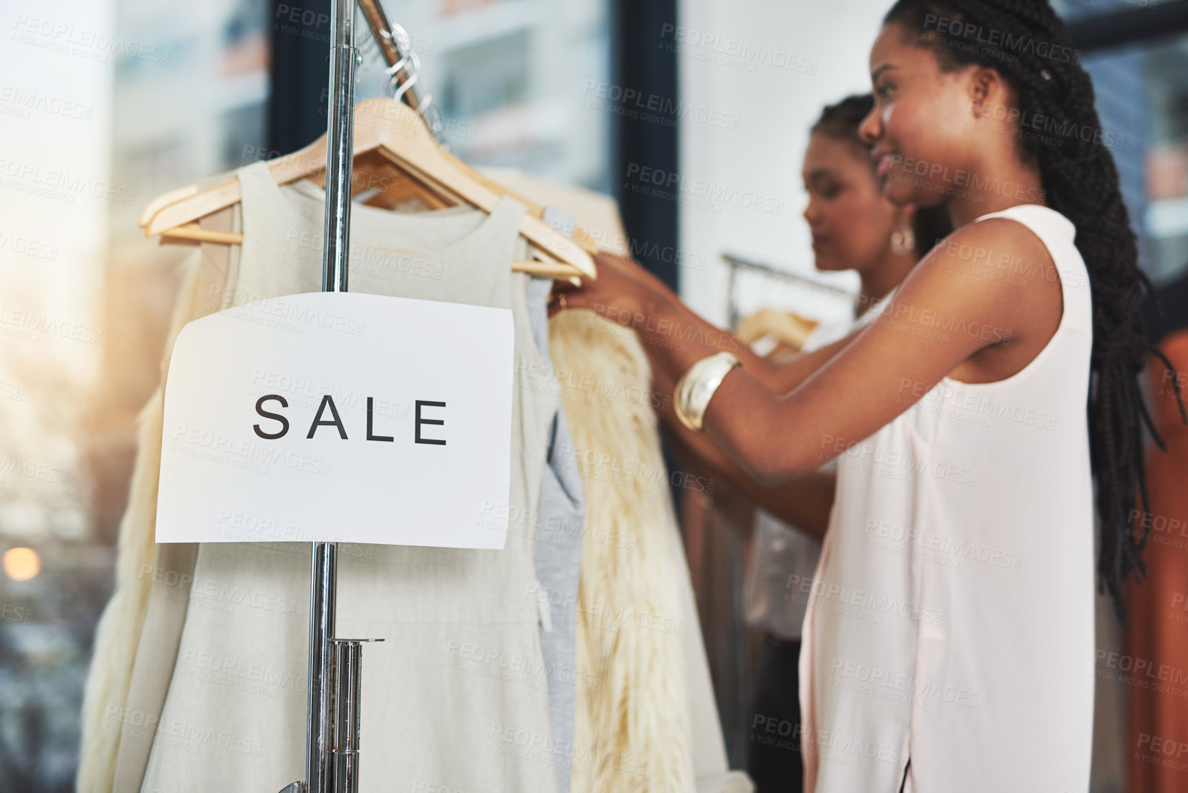 Buy stock photo Cropped shot of two women looking at dresses on a rail with a sign that reads 
