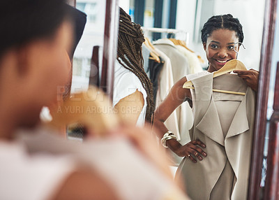 Buy stock photo Cropped shot of a woman in a store holding a garment in front of herself in the mirror