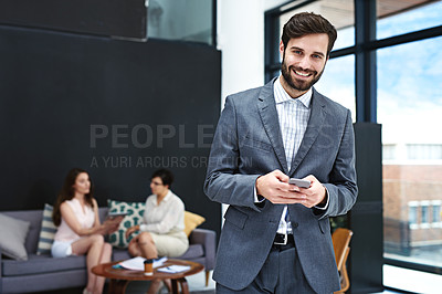Buy stock photo Portrait of a young businessman texting on a cellphone with colleagues in the background