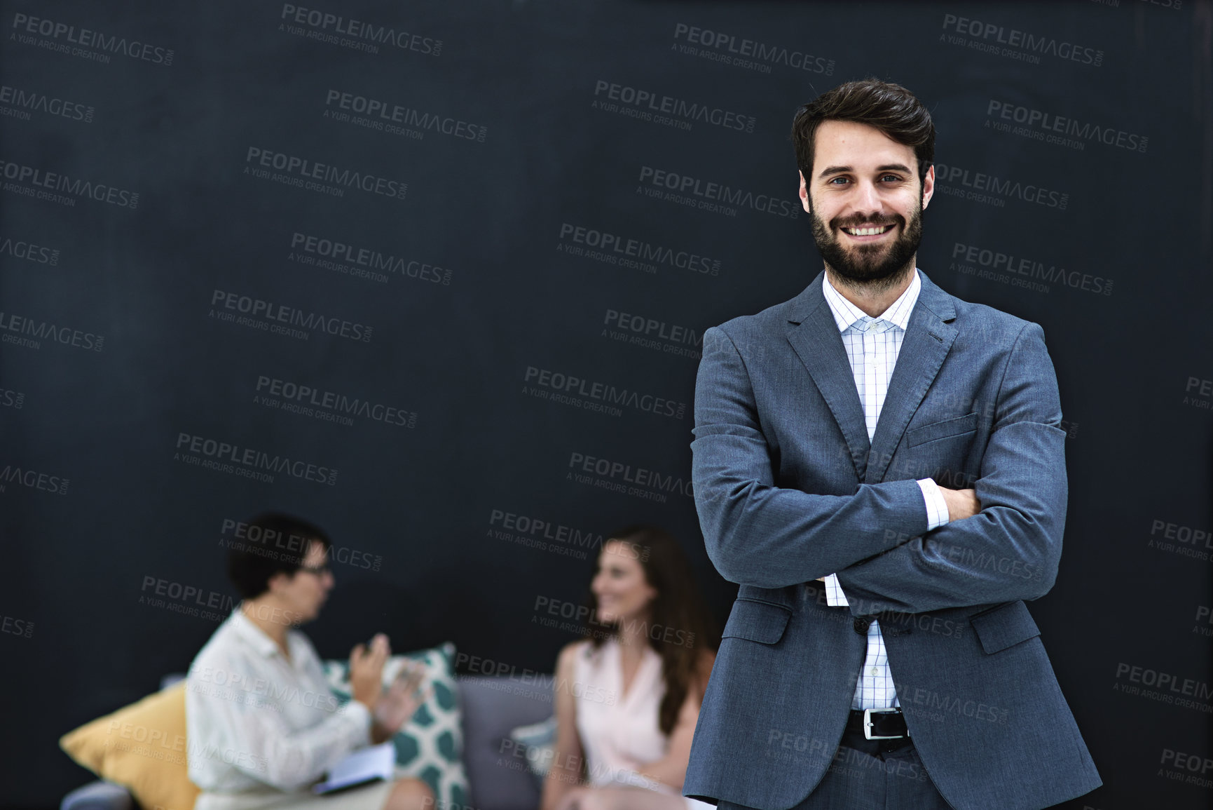 Buy stock photo Portrait of a young businessman standing in a modern office with colleagues in the background