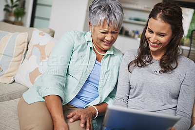 Buy stock photo Smile, tablet and woman teaching senior mother networking on internet, mobile app or website on sofa. Happy, bonding and elderly mom learning digital technology with female person in living room.