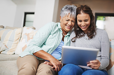 Buy stock photo Help, tablet and woman teaching senior mother networking on internet, mobile app or website on sofa. Happy, bonding and elderly mom learning digital technology with female person in living room.