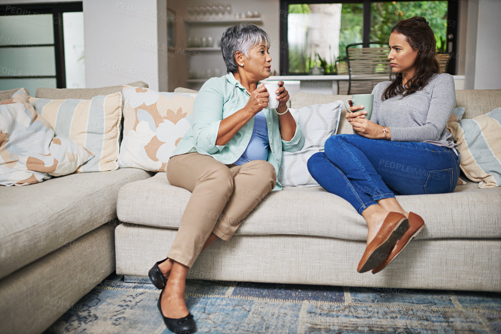 Buy stock photo Support, coffee and mother with daughter on sofa in living room for bonding, conversation and free time. Relax, chat and discussion with women talking in family home for generations, reunion or break