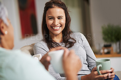 Buy stock photo Shot of a young woman and her mother catching up on the sofa while drinking coffee