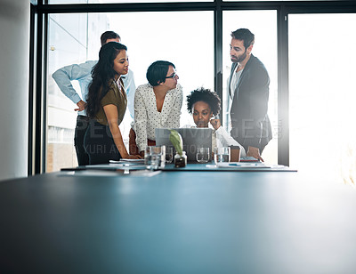 Buy stock photo Cropped shot of a group of businesspeople gathered around a laptop in the office