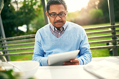 Buy stock photo Mature, man and breakfast with tablet for social in backyard reading news in retirement. Male person, food and tech in morning with newspaper for media with relax, meal and newsletter with glasses 