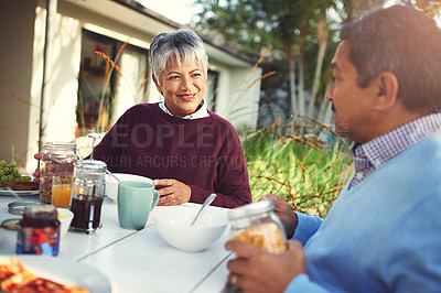 Buy stock photo Shot of a happy older couple enjoying a leisurely breakfast together outdoors