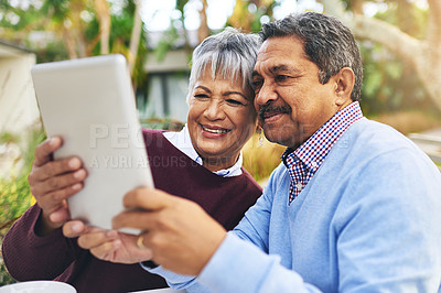 Buy stock photo Shot of an older couple using a digital tablet together outdoors