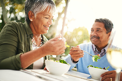 Buy stock photo Shot of a happy older couple enjoying a healthy lunch together outdoors