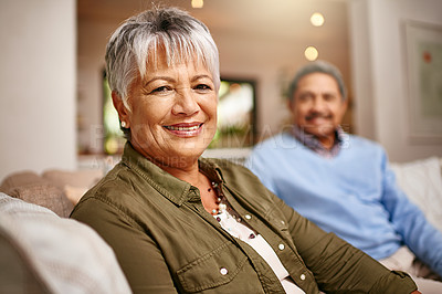Buy stock photo Portrait of a happy older woman relaxing on the sofa with her husband in the background